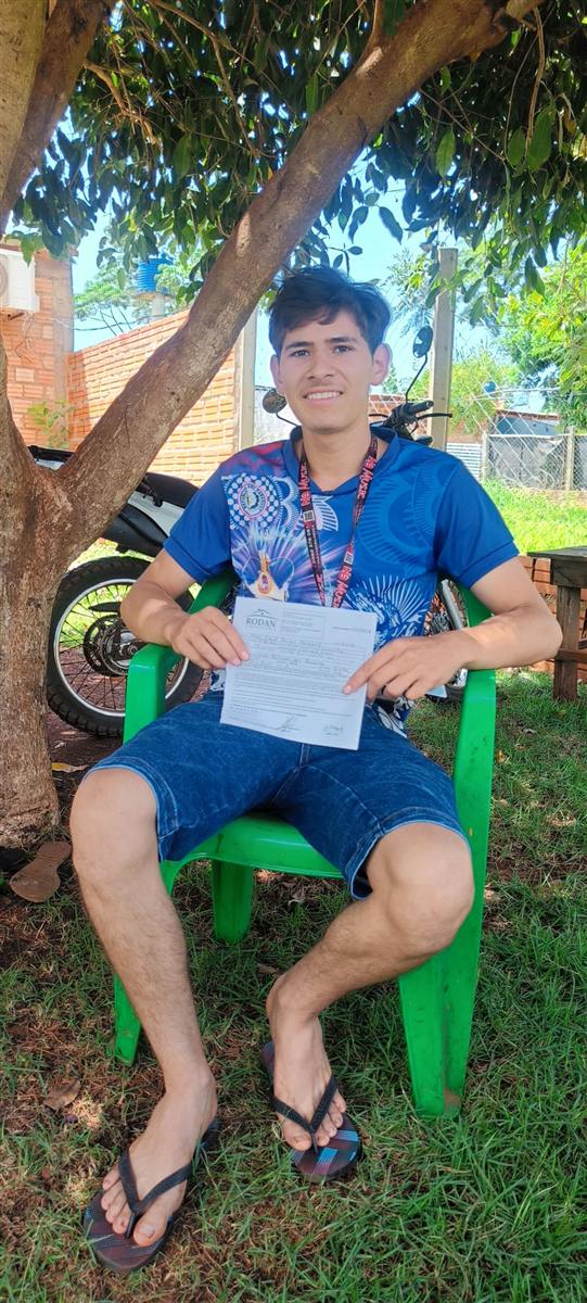 Cliente joven sosteniendo su documento de reserva bajo un árbol